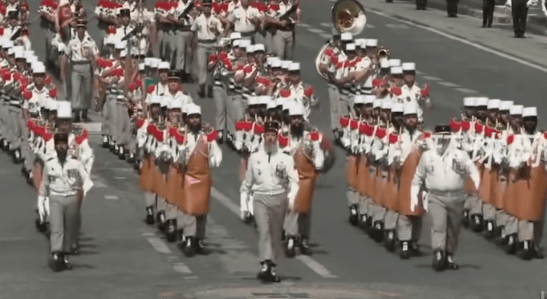 法国阅兵现场，马克龙与第一夫人边看边讨论，其中一方阵人均大胡子，扛着斧头走过